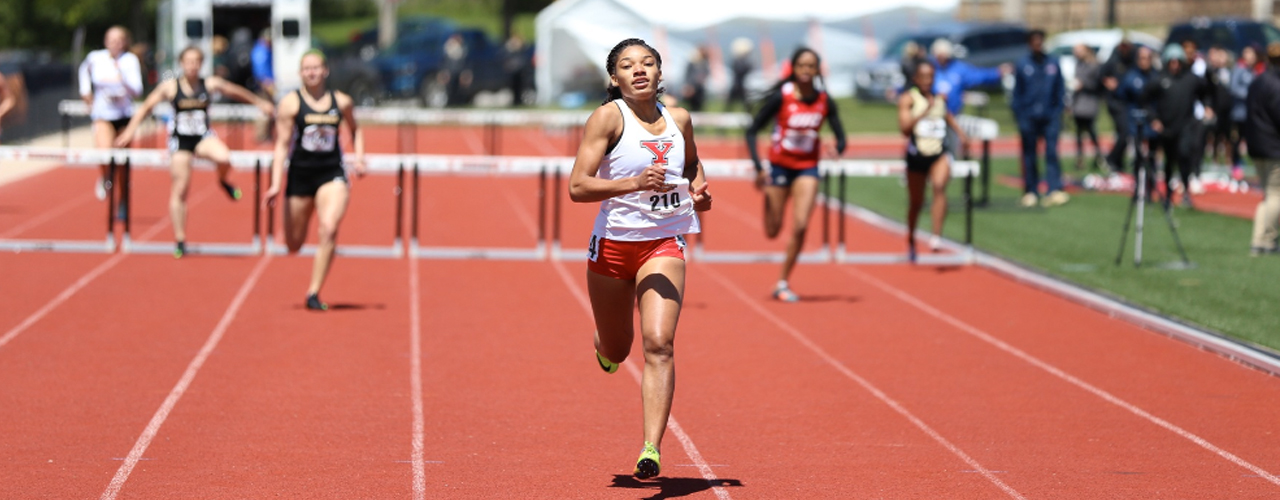 Taylor McDonald jumping over a hurdle in front of the pack.