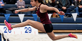 Lily F. jumping over a hurdle.